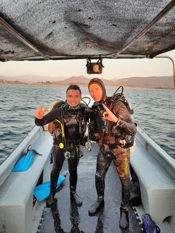 Deux plongeurs souriants équipés à bord d'un bateau de plongée