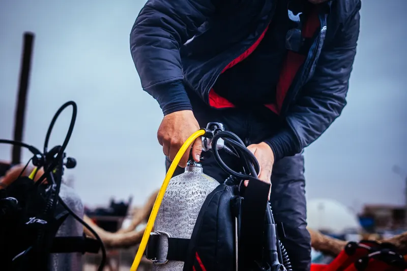 Préparation d'une bouteille de plongée par un opérateur en veste