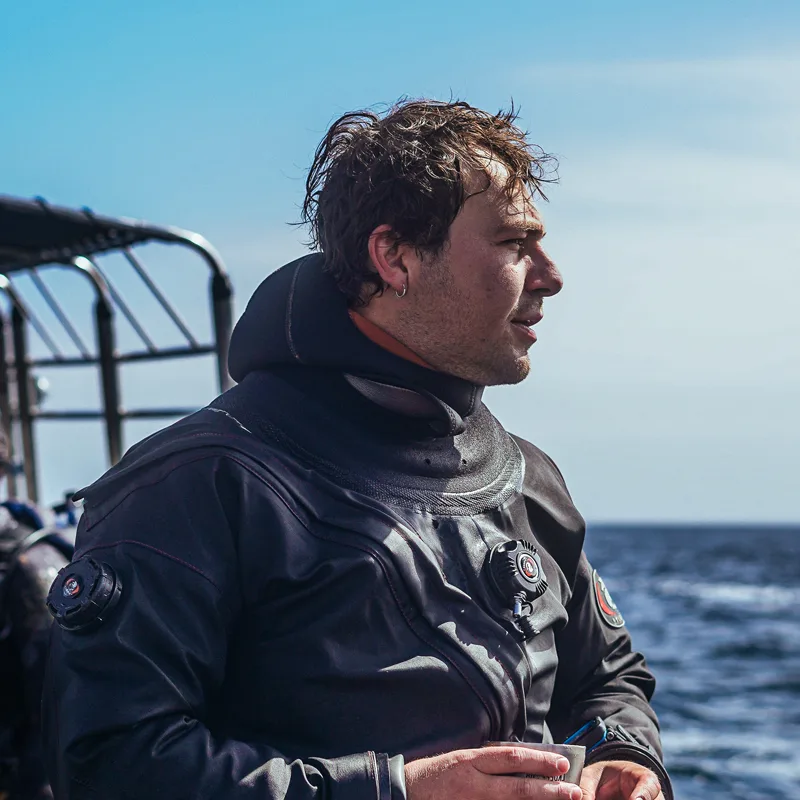 Plongeur en combinaison noire regarde vers l'horizon en mer