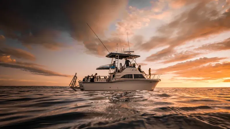 Bateau de plongée en mer avec des personnes à bord au coucher du soleil