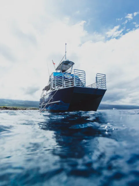 Bateau de plongée bleu foncé à quai, vue sous-marine claire