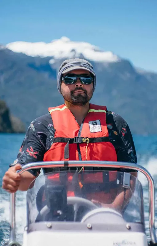 Homme au volant d'un bateau de plaisance, portant un gilet rouge