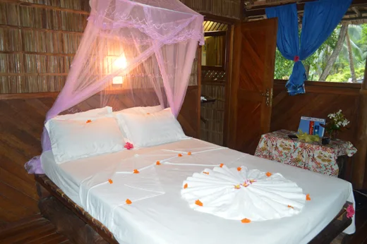 Chambre avec lit à baldaquin décoré de fleurs et serviettes