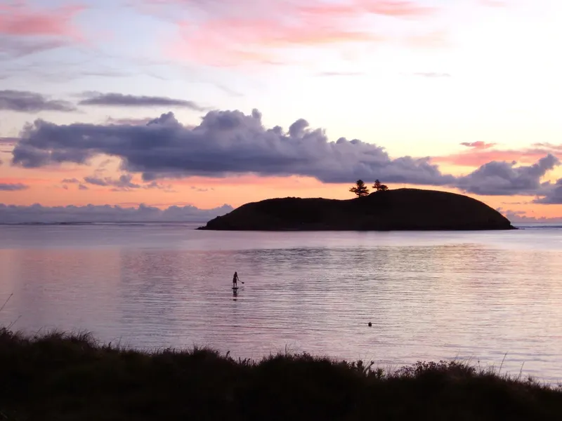 Silhouette d'une personne debout dans l'eau au coucher du soleil