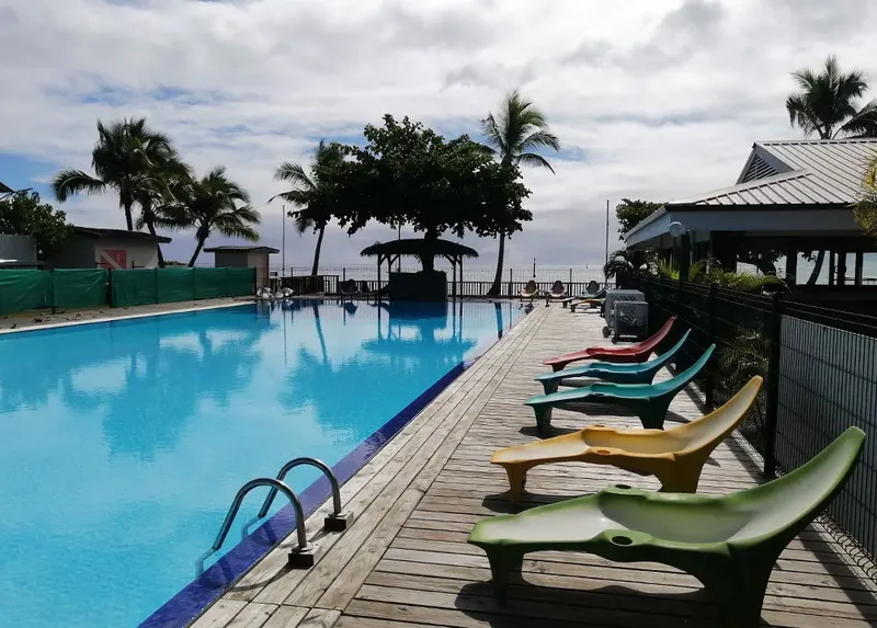 Piscine bleue avec transats colorés et végétation tropicale ensoleillée