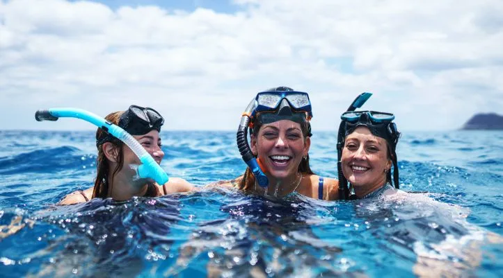 Trois femmes souriantes avec masque et tuba dans l'eau