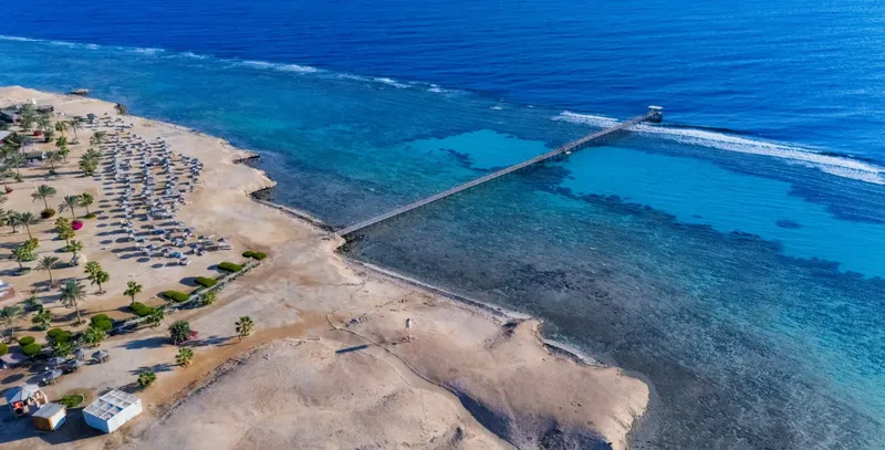 Vue aérienne d'une plage avec un ponton menant vers la mer
