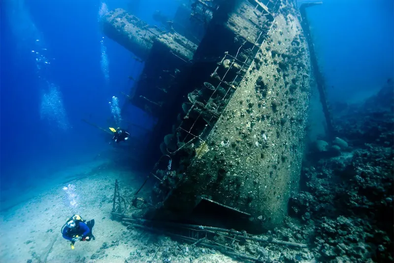 Deux plongeurs explorent l'épave d'un grand navire sous-marin