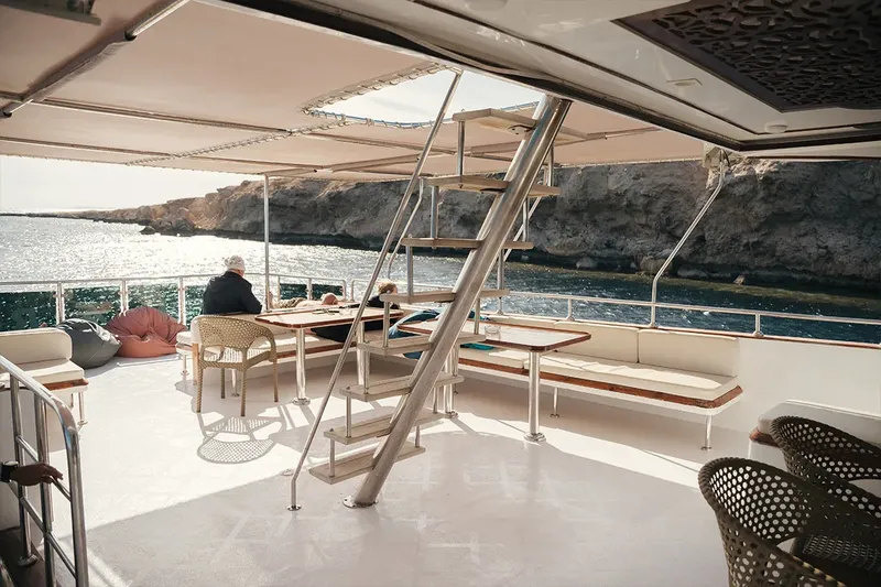 Terrasse d'un bateau avec des passagers assis à table ensoleillée