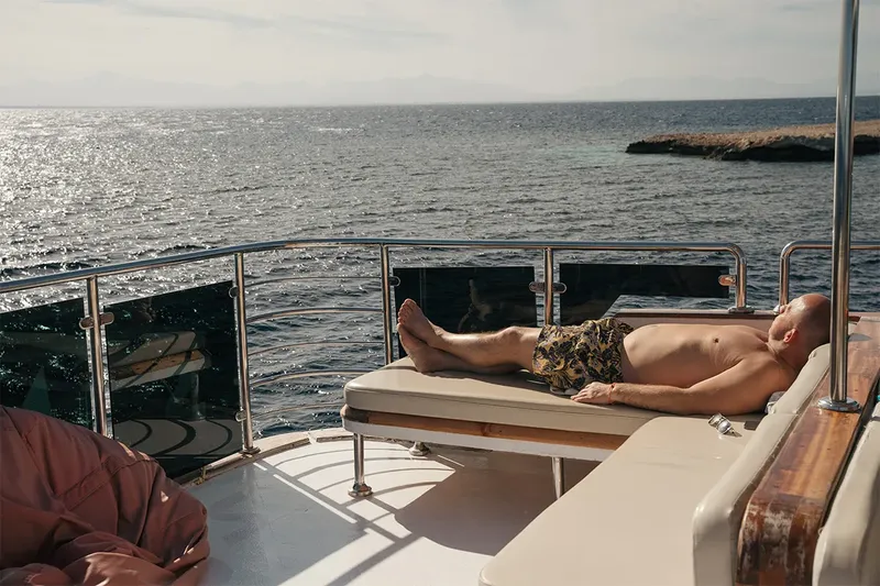 Homme se relaxant au soleil sur le pont d'un bateau de plongée