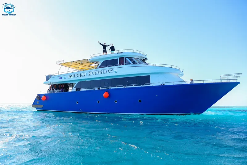 Grand bateau de plongée bleu et blanc avec deux personnes sur le pont