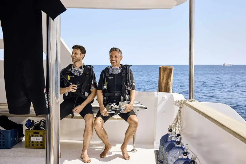 Deux plongeurs souriants assis sur un bateau en mer