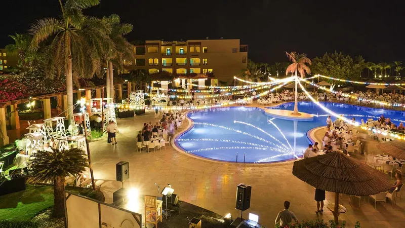Soirée festive avec tables illuminées autour d'une piscine et des convives