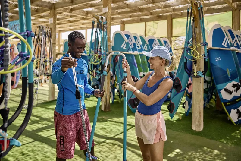 Deux personnes manipulent du matériel de kitesurf dans un local spacieux