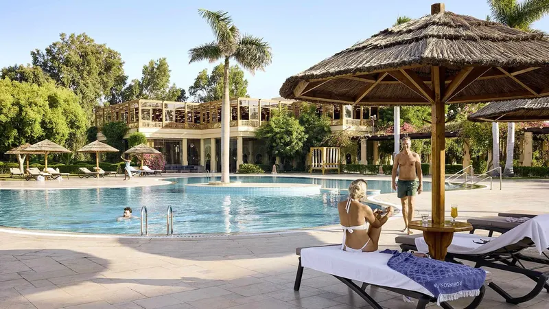 Piscine avec transats, parasols et bâtiment en arrière-plan