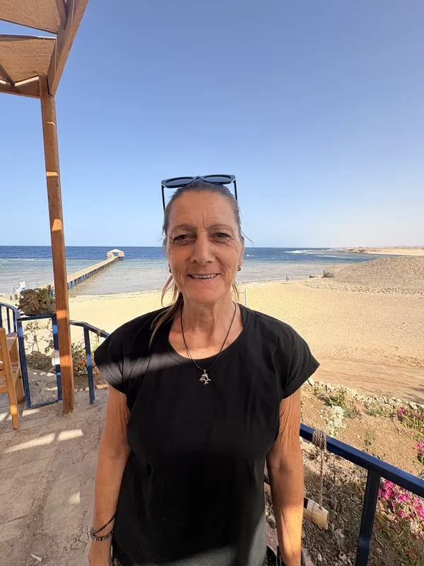 Femme souriante debout sur une terrasse avec vue sur la mer