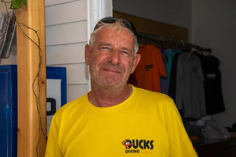 Homme souriant portant un t-shirt jaune avec un logo de plongée