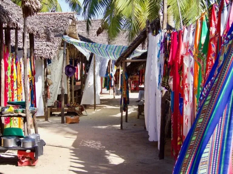 Marché artisanal sur une plage ensoleillée avec des textiles colorés