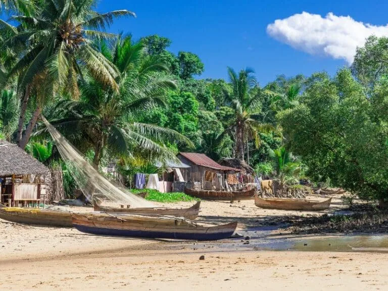 Plage tropicale avec des pirogues en bois et végétation luxuriante