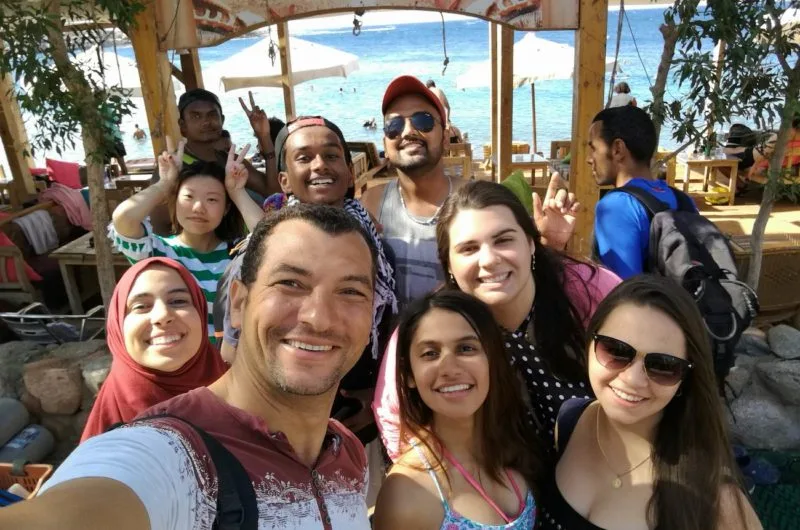 Groupe de personnes souriantes posant pour un selfie en extérieur