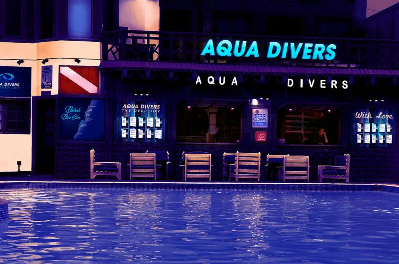 Façade d'un centre de plongée illuminée la nuit avec des chaises longues