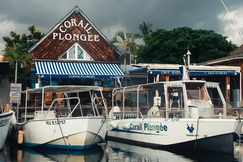 Bateaux de plongée amarrés devant un centre avec une devanture bleue et blanche