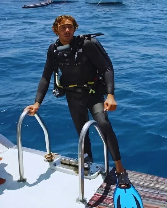 Plongeur en combinaison se prépare à entrer dans l'eau depuis un bateau
