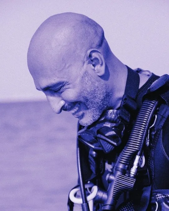Plongeur souriant avec son équipement, regardant vers le bas
