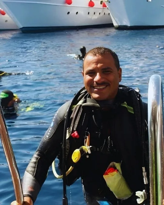 Plongeur souriant équipé en surface près d'un bateau de plongée