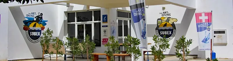 Façade d'un centre de plongée avec enseignes et drapeaux suisses