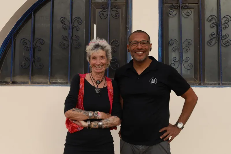 Deux personnes souriantes posent devant un mur décoratif bleu et blanc