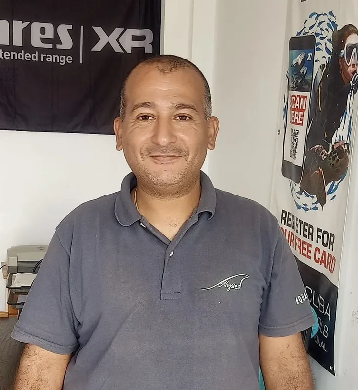 Portrait d'un homme souriant, portant un polo bleu, devant un mur