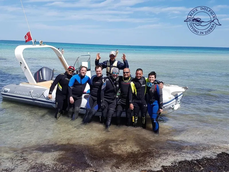 Groupe de plongeurs souriants près d'un bateau semi-rigide dans l'eau