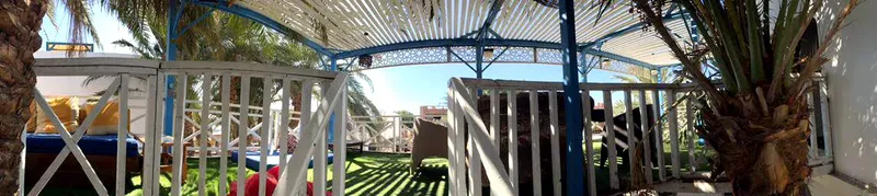 Structure métallique avec végétation, espace extérieur ombragé et mobilier