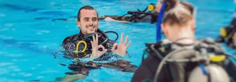 Instructeur de plongée souriant guide un élève en piscine avec équipement