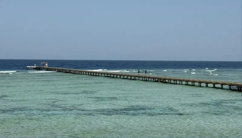 Long ponton en bois s'étendant sur une mer turquoise et calme