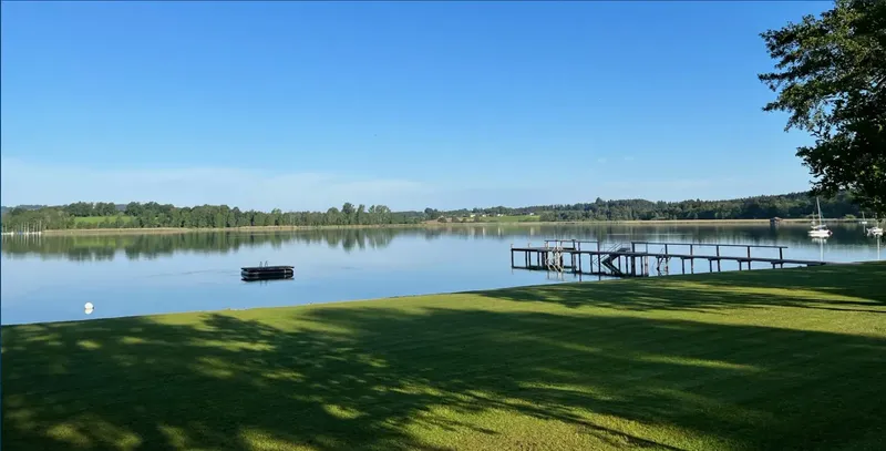 Vue d'un lac avec un bateau, un ponton et de la verdure