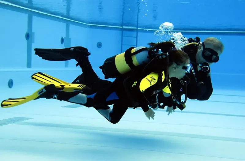 Deux plongeurs en formation nagent sous l'eau dans une piscine