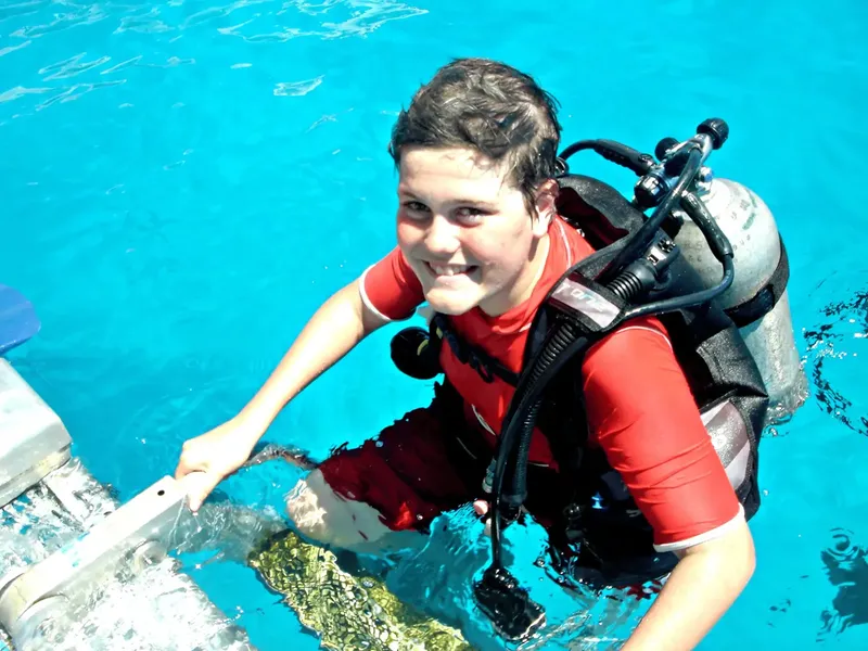 Plongeur souriant en préparation, équipé, descendant un escalier aquatique
