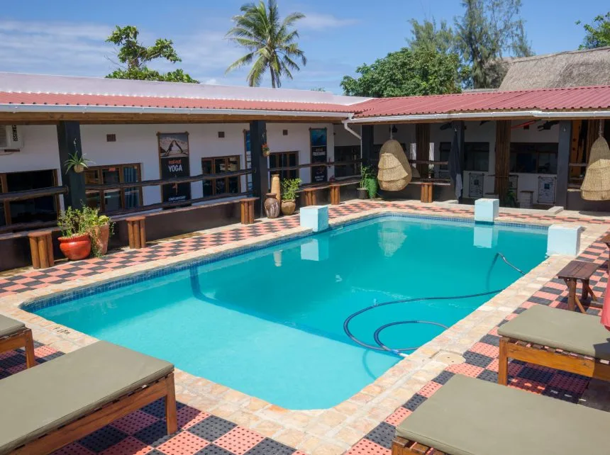 Piscine rectangulaire devant un bâtiment avec végétation tropicale