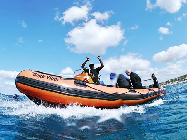 Personnes à bord d'un bateau pneumatique orange sur l'océan