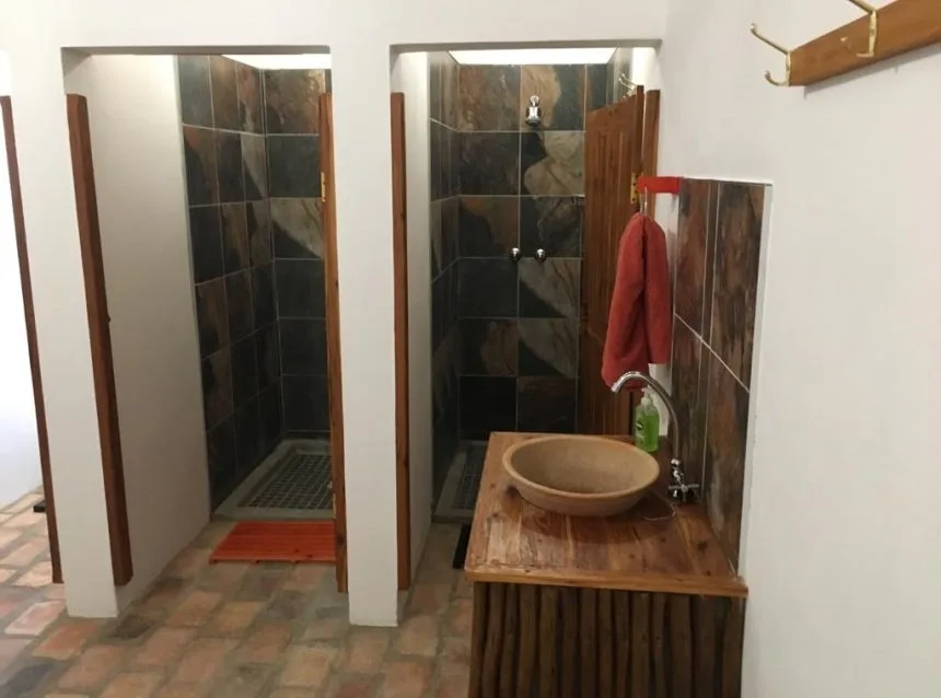 Deux douches carrelées avec un lavabo en pierre et un tapis orange