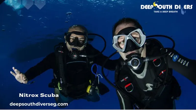 Deux plongeurs avec équipement complet, souriants dans l'eau bleue
