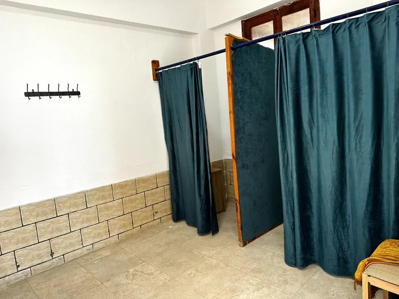 Vestiaires avec rideaux verts et murs en briques claires éclairés