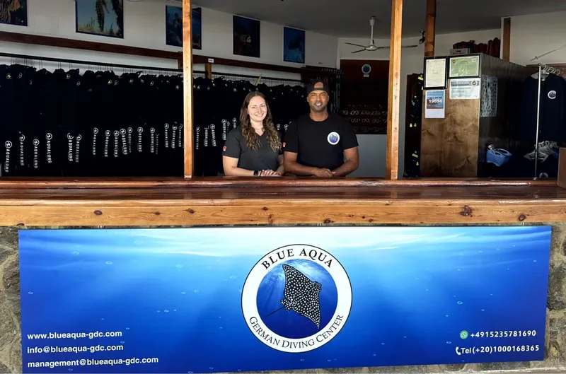 Deux moniteurs de plongée souriants derrière un comptoir en bois