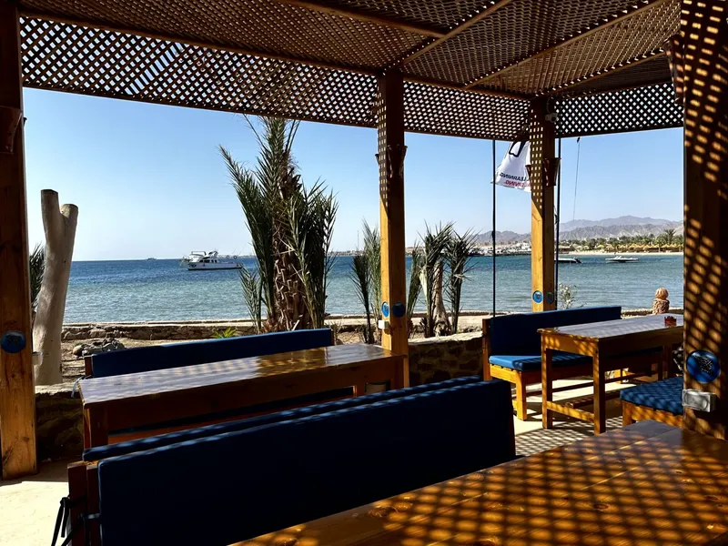 Terrasse ombragée avec vue sur la mer et quelques bateaux amarrés