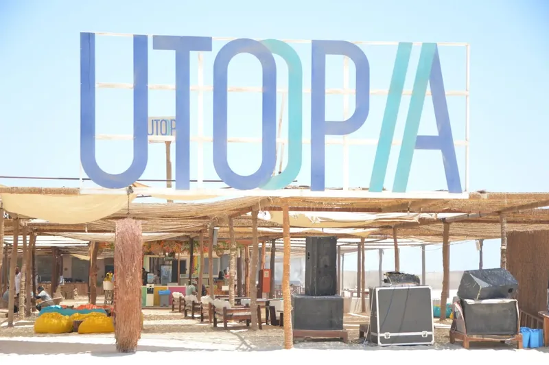 Grande enseigne UTOPIA au-dessus d'une structure abritant des espaces de détente