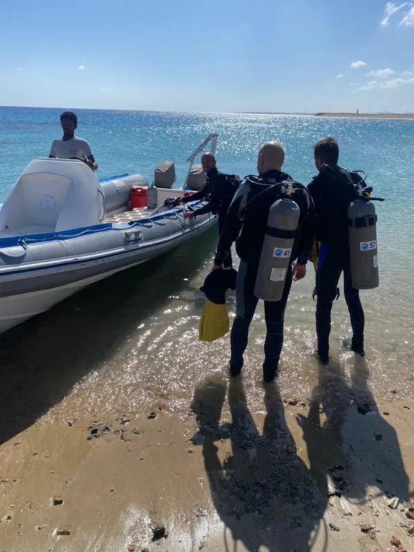 Plongueurs équipés se dirigent vers un bateau pneumatique sur une plage