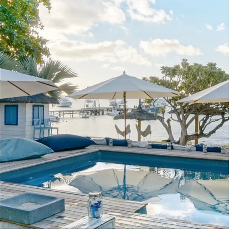 Terrasse avec piscine, parasols, bâtiments et bateaux au loin
