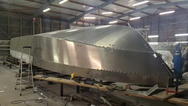 Coque de bateau en métal argenté en construction dans un atelier